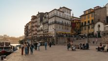 Riverside promenade in Porto with colorful historic buildings and people strolling along the waterfront at sunset on the Portuguese Camino.