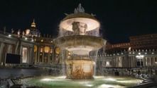 Illuminated fountain at St. Peter's Square at night with St. Peter's Basilica dome and colonnade visible in background. Water cascades from tiers.