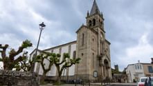 Stenkirke med højt klokketårn og buede vinduer langs pilgrimsruten Camino de Santiago fra Sarria til Santiago.
