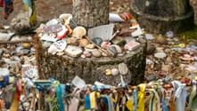 Stone marker on Portuguese Camino decorated with scallop shells, stones, ribbons, and pilgrim mementos at its base and hanging from colorful ribbons.