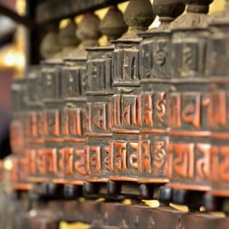 Buddhistiske bødehjul i Swayambhunath Række af udsmykkede buddhistiske bødehjul med sanskrit-indskrifter ved Swayambhunath-templet i Nepal. En hånd ses række mod hjulene.