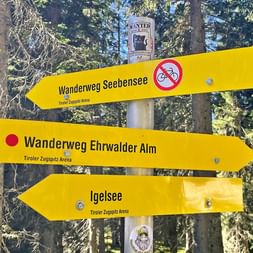 Gule vandreskilte i skov med retninger til Wanderweg Seebensee, Wanderweg Ehrwalder Alm og Igelsee nær Zugspitze.