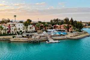 Luftfoto af Sultan Bey Hotel i El Gouna med hvide og terracottafarvede bygninger, pool og tyrkisblå lagune ved solnedgang.