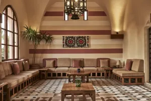 Elegant lounge på Sultan Bey El Gouna med hvælvet loft, stribede vægge, indbyggede siddepladser, træborde og ternet gulv.