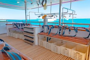 Dykdäck på Long Island liveaboard med organiserade utrustningsstationer, träbänkar, förvaringskorgar och turkos havsutsikt.