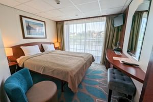 Modern övre däck hytt på MS SE-MANON med två enkelsängar, stort fönster, skrivbord, turkos fåtölj och flodvy.