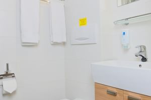 Kompakt bad på MS Normandie med hvitt vegghengt toalett, treskap, hvit vask, speil og dekorativ flisekant.