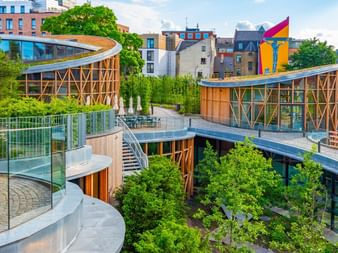 Modernt H.C. Andersen Museum i Odense med böjda trästrukturer, gröna tak och trädgårdar integrerade i stadslandskapet.