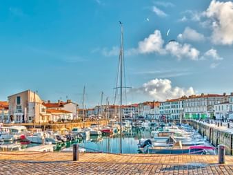 La Rochelle havn med talrige sejlbåde og yachter fortøjet i roligt vand, omgivet af historiske hvide bygninger med røde teglstenstage.