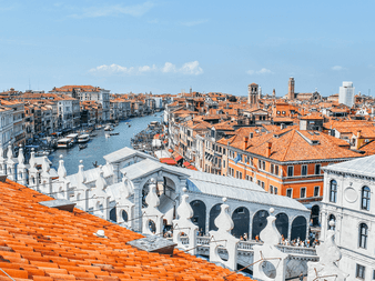 Luftfoto af Venedig med terracotta-tage, Canal Grande med både og den hvide Rialtobro. Historiske bygninger langs kanalen.