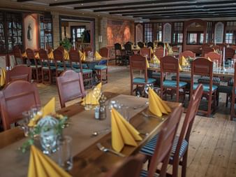 Traditionelt norsk restaurantinteriør med træborde, brune læderstole, gule servietter og dekorative vægpaneler på Fillefjellstuene.