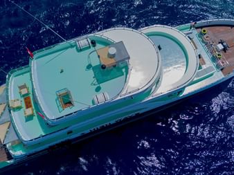 Luftfoto af High Wave liveaboard skib med hvidt og grønt skrog sejlende gennem dybt blå havvand.
