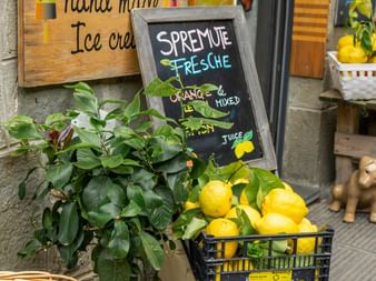 Italian street vendor display with fresh lemons in crates, lemon tree, and chalkboard sign advertising fresh squeezed juice in Cinque Terre.