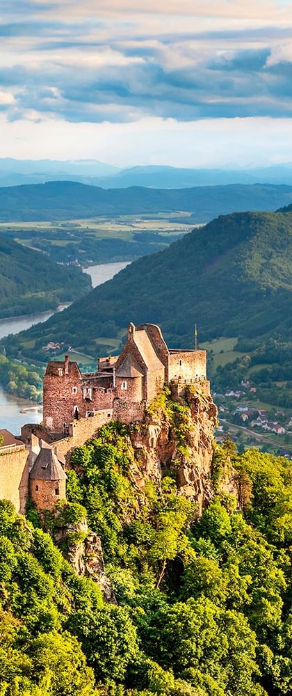 Middelalderlige ruiner af Aggstein slot på en klippetop med udsigt over den snoede Donau gennem den grønne Wachau-dal.