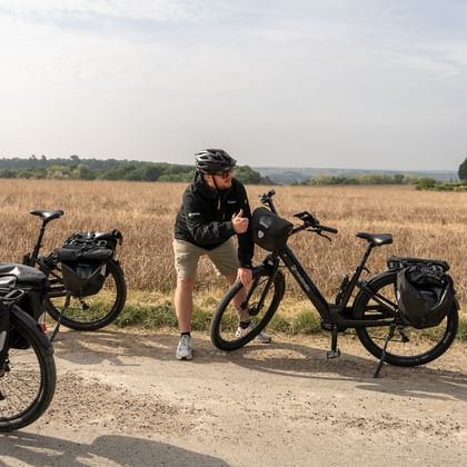 Två cyklister med hjälmar tar en paus bredvid sina turistcyklar med väskor på en landsväg i Loire-dalen, Frankrike.