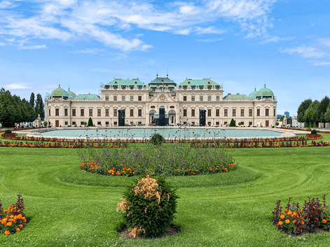 Øvre Belvedere i Wien med grønne kobberkupler, symmetrisk barokfacade og velholdte haver med farverige blomsterbede.