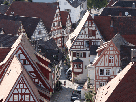 Luftfoto af traditionelle bindingsværkshuse med røde og brune tage i Bad Wimpfen, Tyskland. En smal gade løber mellem de historiske bygninger.