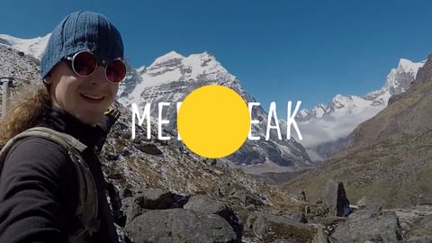 Mera Peak mountaineer in Himalayas Smiling mountaineer with sunglasses and beanie taking selfie in Mera Peak region with snow-capped Himalayan mountains in background.